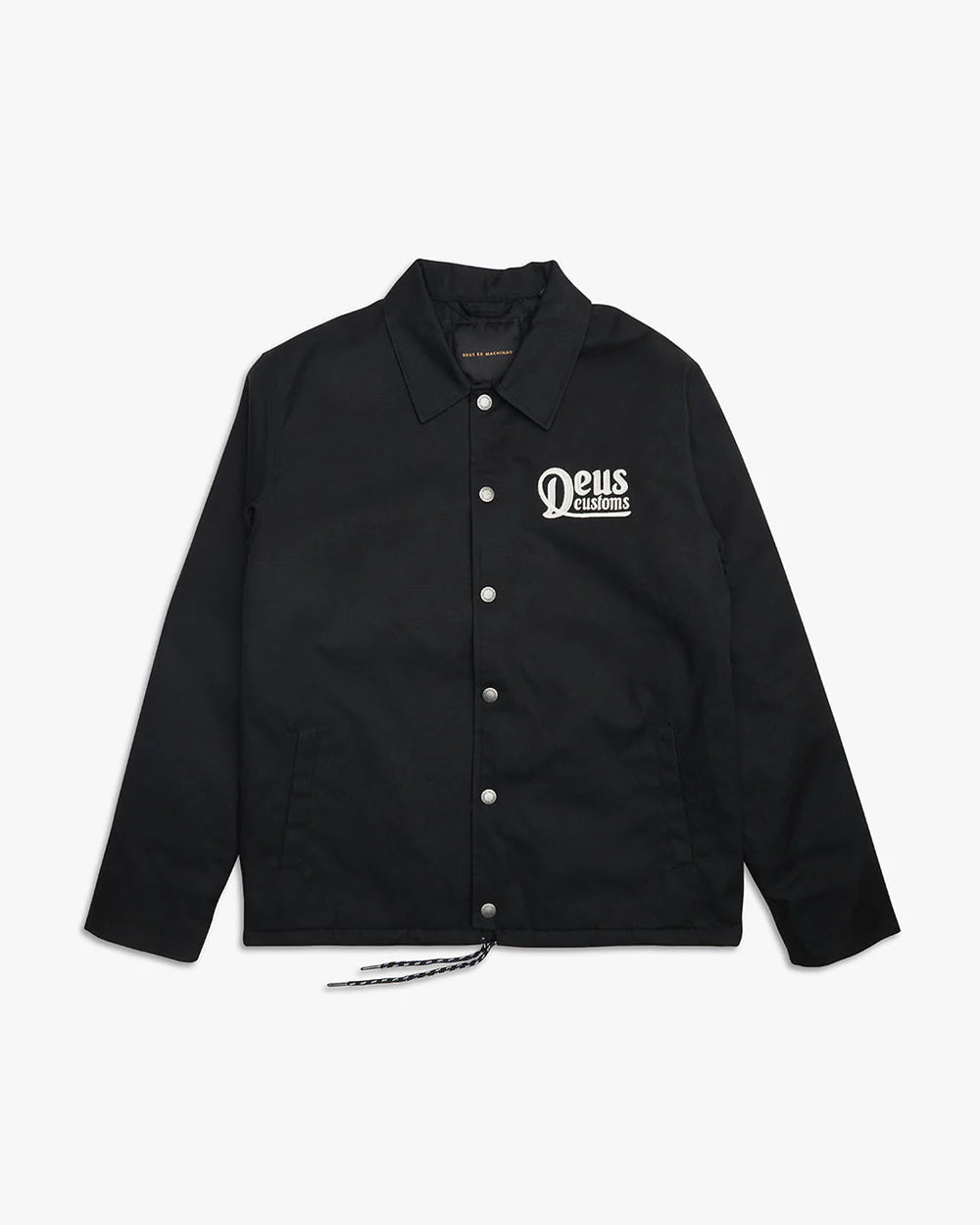 Wasserabweisendes Coach-Jacket von Deus in Schwarz mit silbernen Knöpfen. Auf der Brust ist eine kleine Stickerei in weiß "Deus Customs" angebracht.
