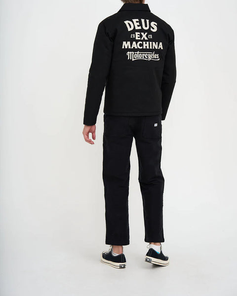 Ein männliches Model trägt die Hose mit einer schwarzen Jeans und schwarzen Chucks.