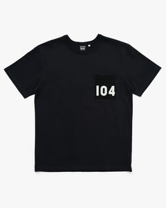Locker geschnittenes T-Shirt von Deus in Anthrazit mit einer schwarzen Brusttasche. Auf der Brusttasche steht in weißen Zahlen "104"