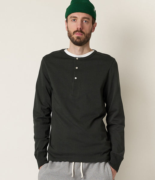 Merz b. Schwanen Henley in der Farbe Forest, ein dunkles Grün. Ein männliches Model trägt das Shirt