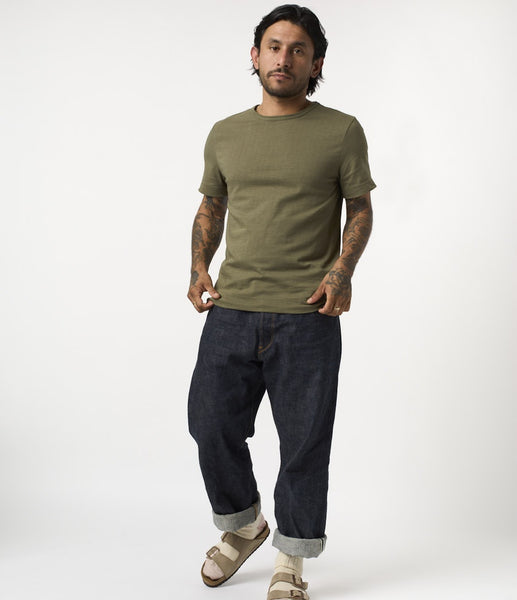 Merz b. Schwanen 215 T-Shirt in der Farbe Army. Ein männliches Model trägt das Shirt in Kombination mit einer locker geschnitten Raw Denim