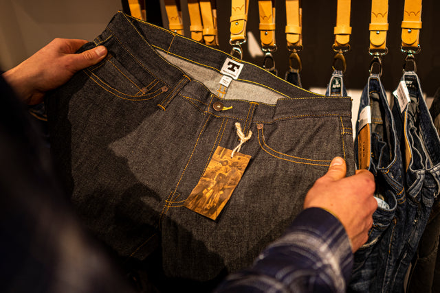 Die Tellason Jeanshose in Raw Denim wird betrachtend in den Händen gehalten.