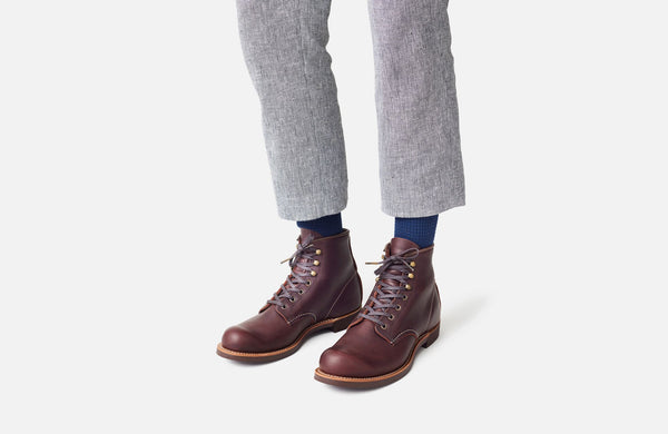 Ein männliches Model trägt den Schuh mit blauen Socken und einer grauen, schmal geschnittenen Stoffhose.